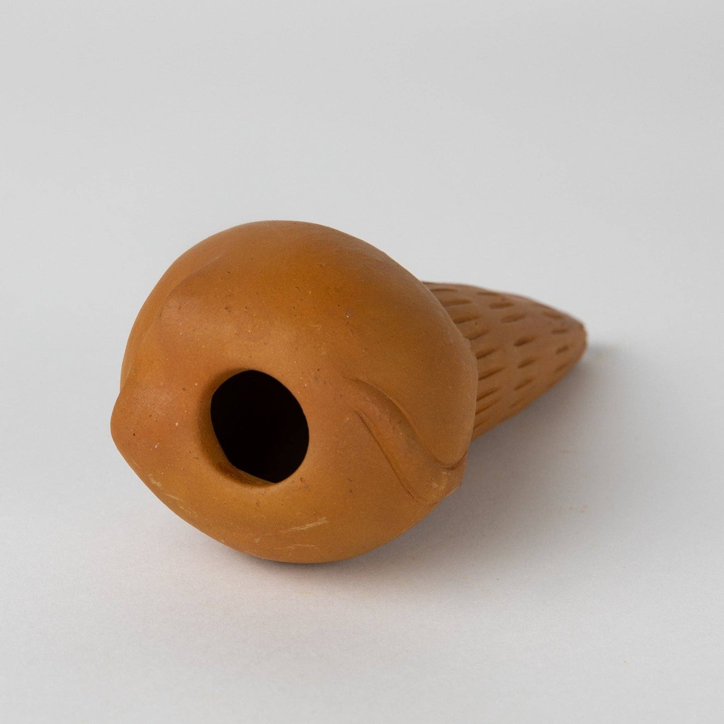 Top view of terracotta cat-shaped water device on a white background