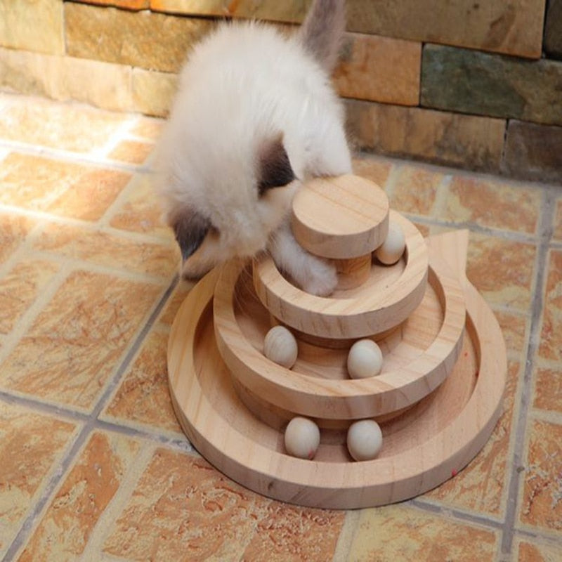 White cat with grey ears playing with the a three-tier wooden track toy on a tile floor