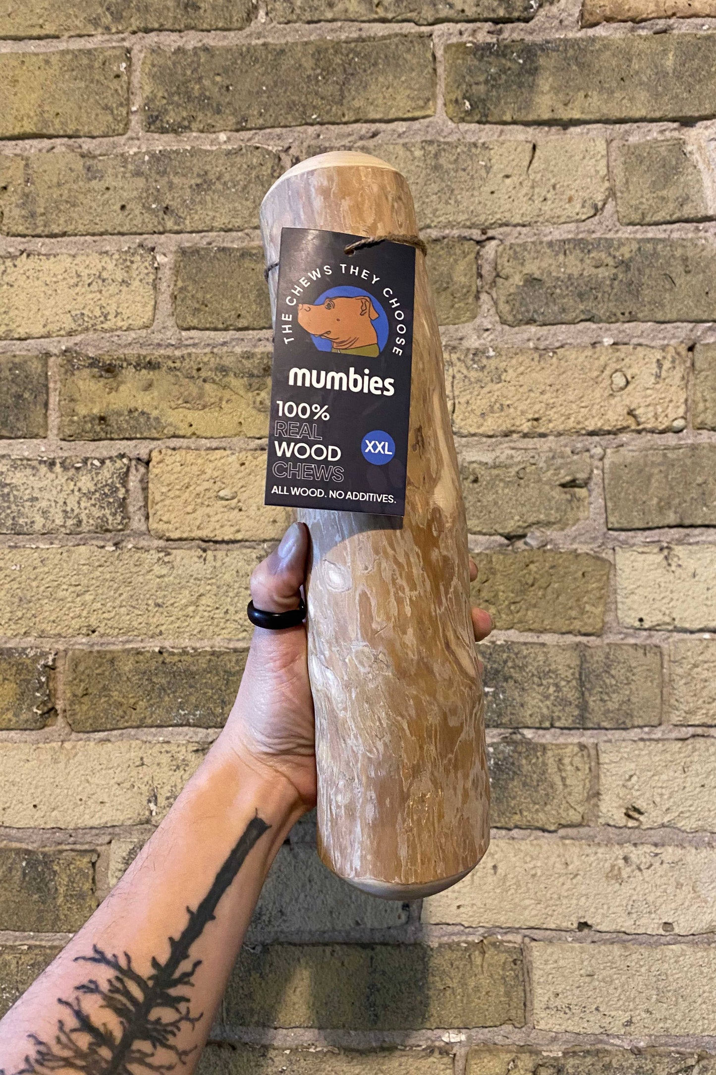 Wooden product with 'mumbies' branding held against a brick wall.