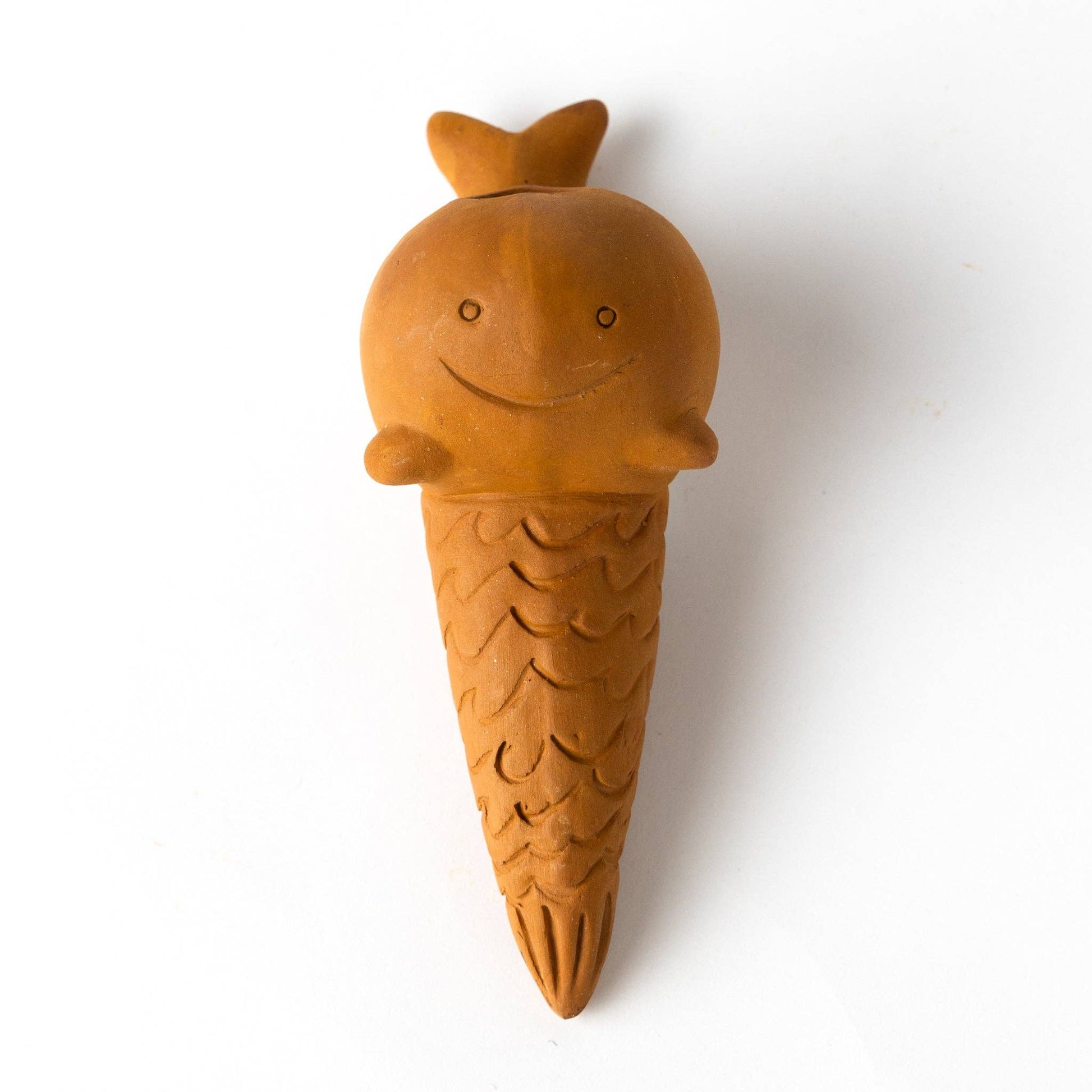 Terracotta whale-shaped watering device on white background